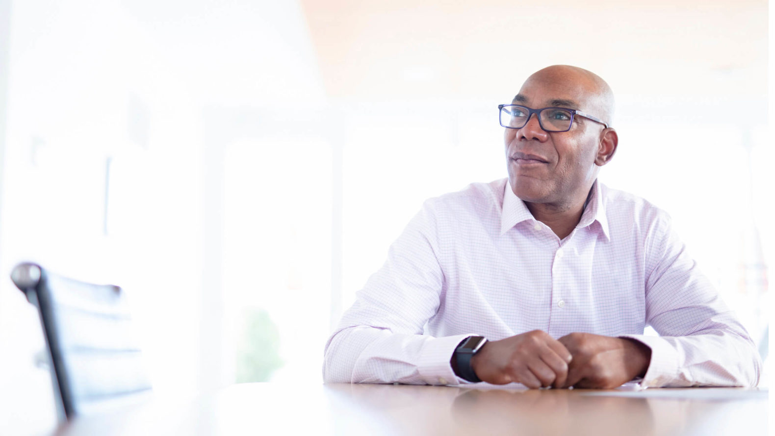 professional in collared shirt sitting at a desk with natural lighting coming from windows out of focus in the background