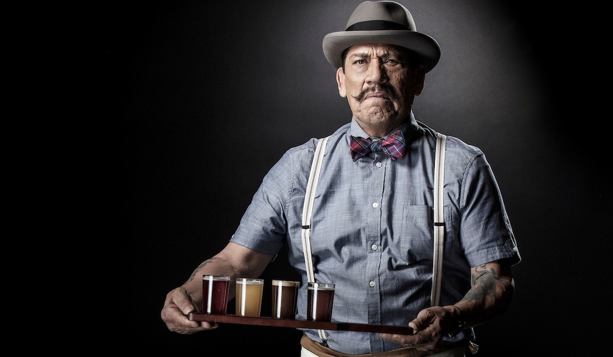 Production still of man with top hat holding flight of beer