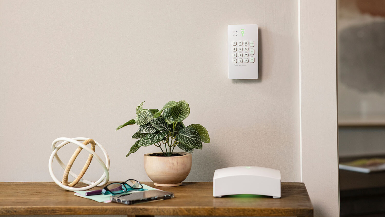 various office items on a desk with security system number pad on wall