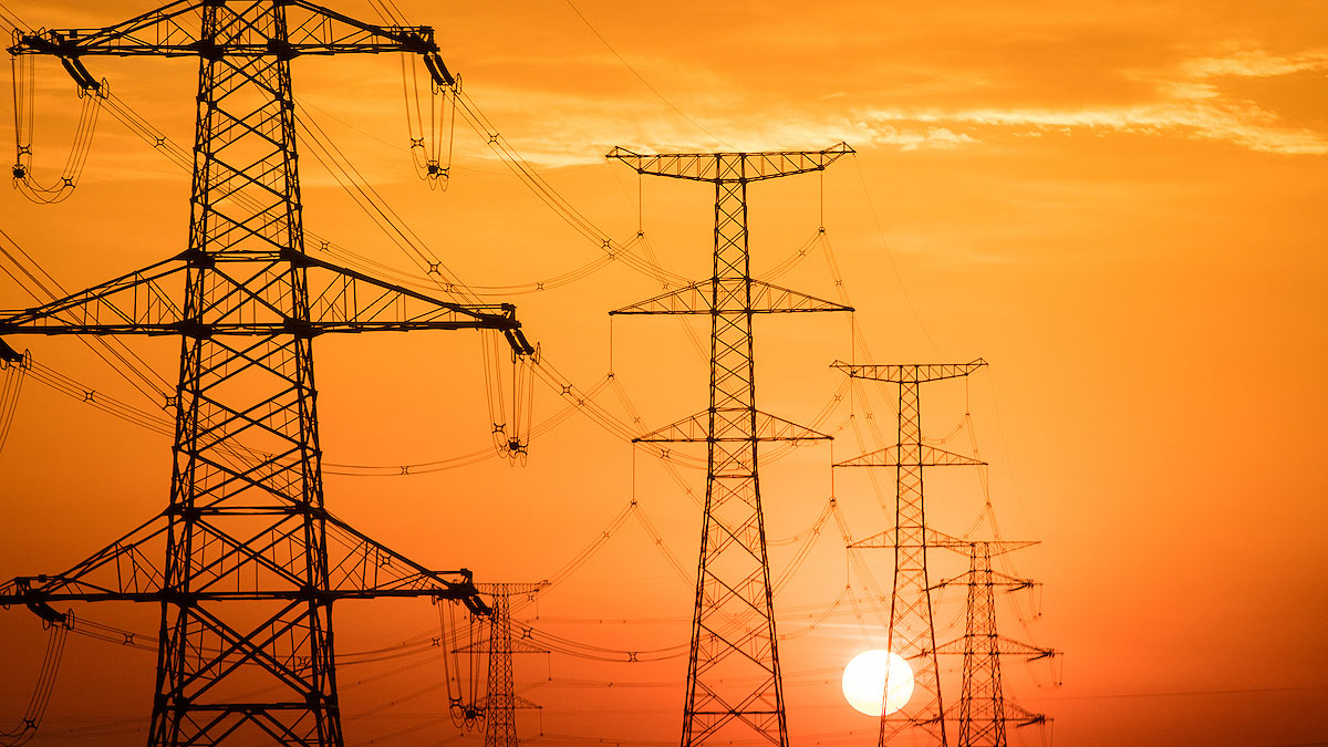 landscape of power lines with glowing orange sun in background