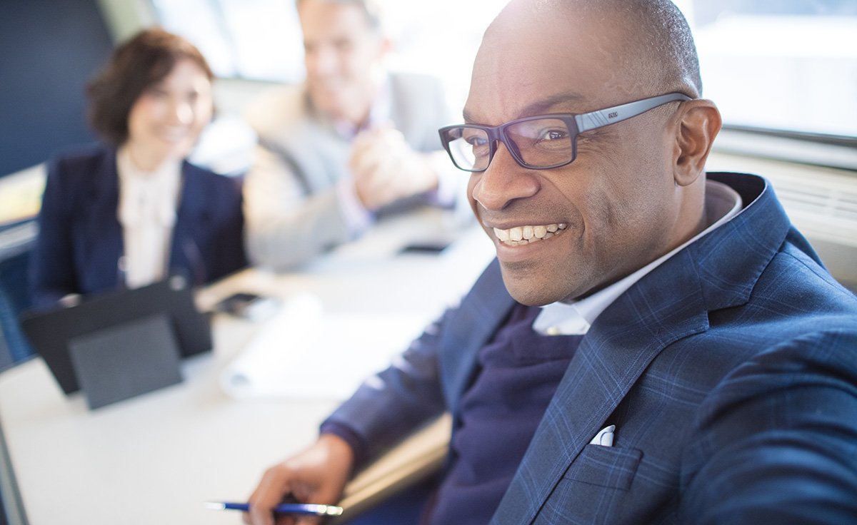 Corporate employee wearing plaid suit jacket and glasses smiling