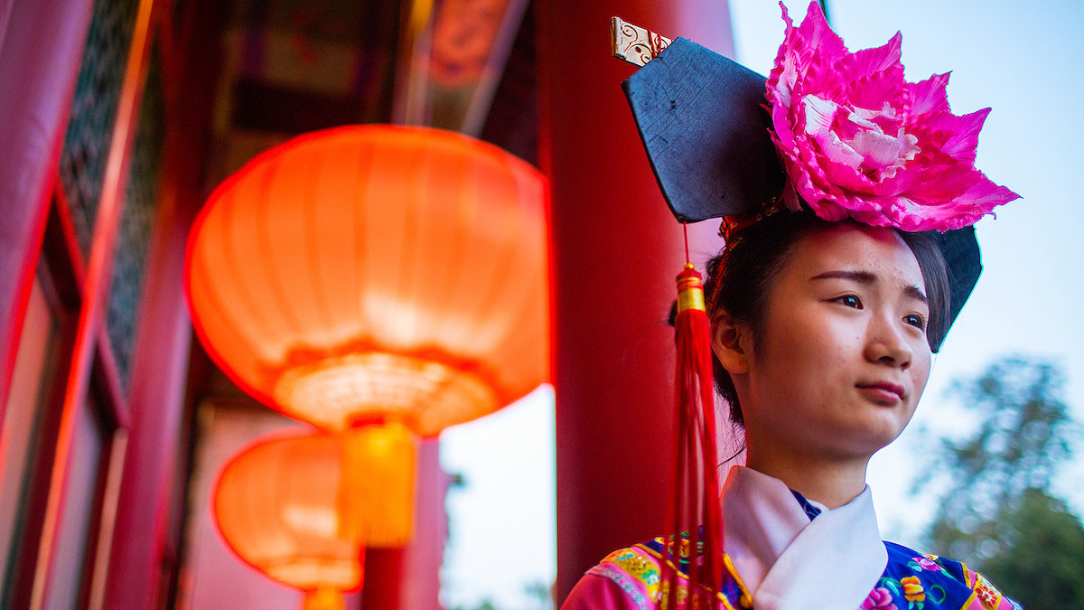 female wearing pink flower headpiece with red tassel hanging