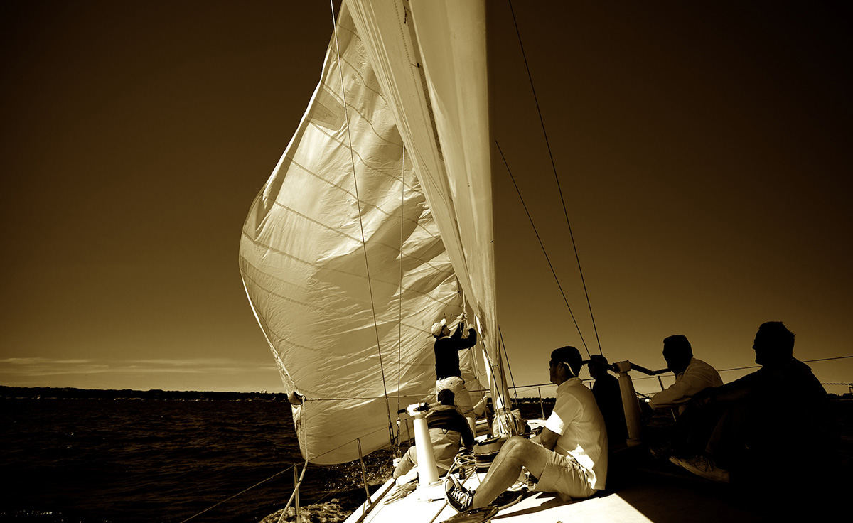 group of male individuals sailing sailboat on body of water