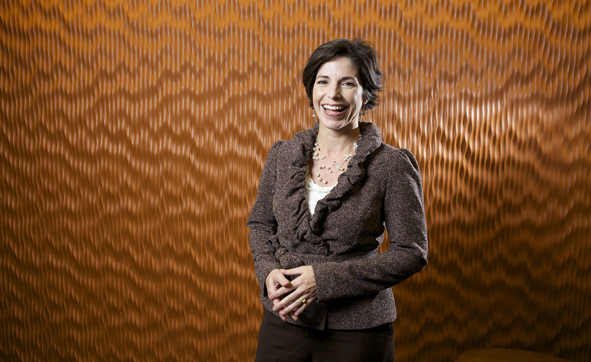 short brown haired female with neckless standing in front of brown patterned background