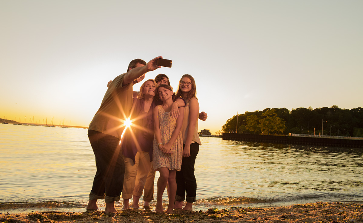 family taking selfie on shore of lake