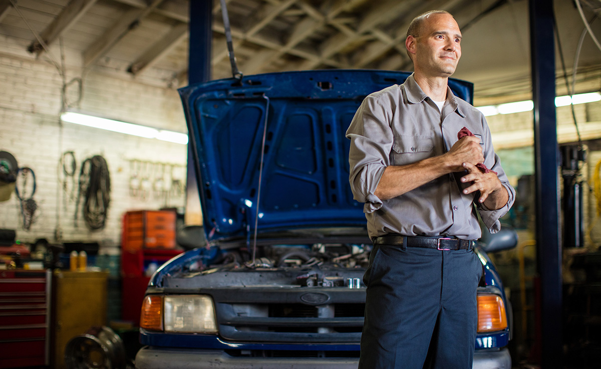 automotive repairman wiping hands standing in shop