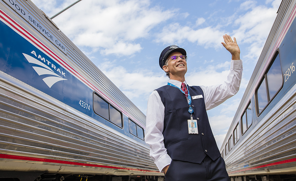 amtrak employee waving to trains at station