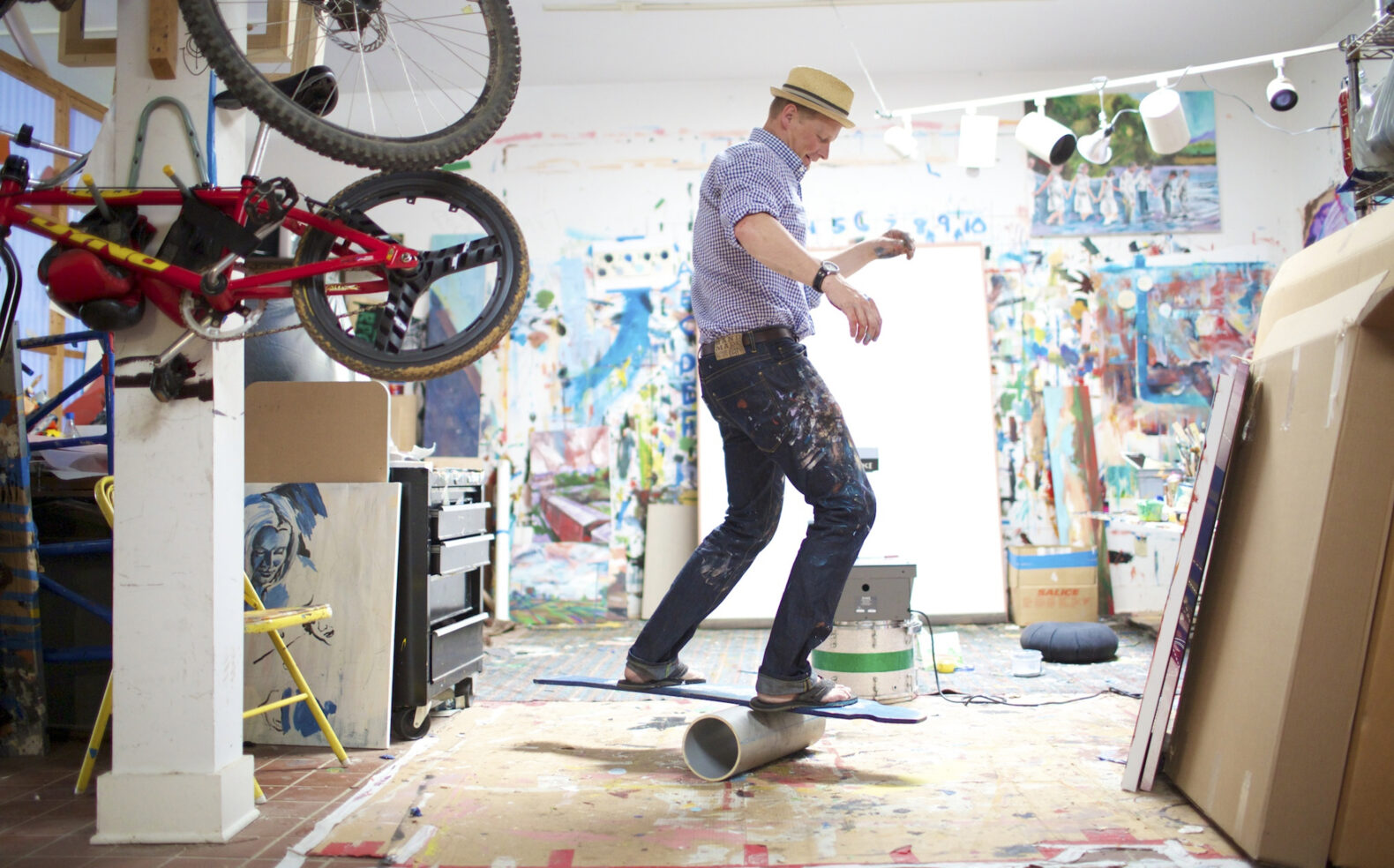 artist riding wooden board on hollow tube in creative space