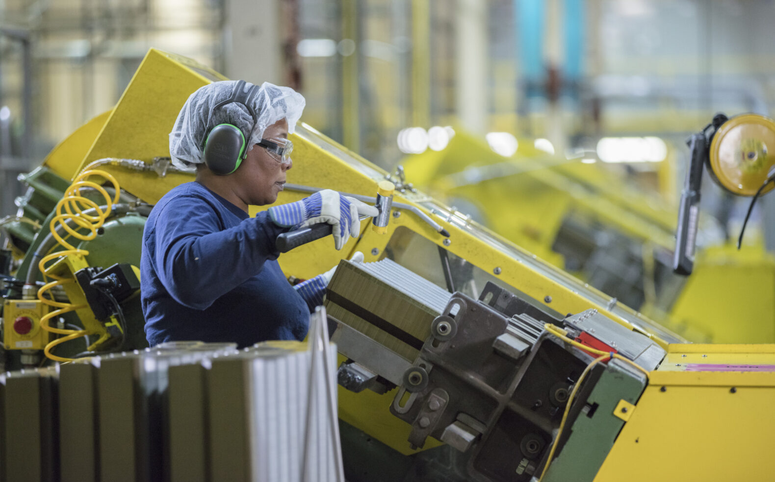 woman with hair net and ear protection working in factory