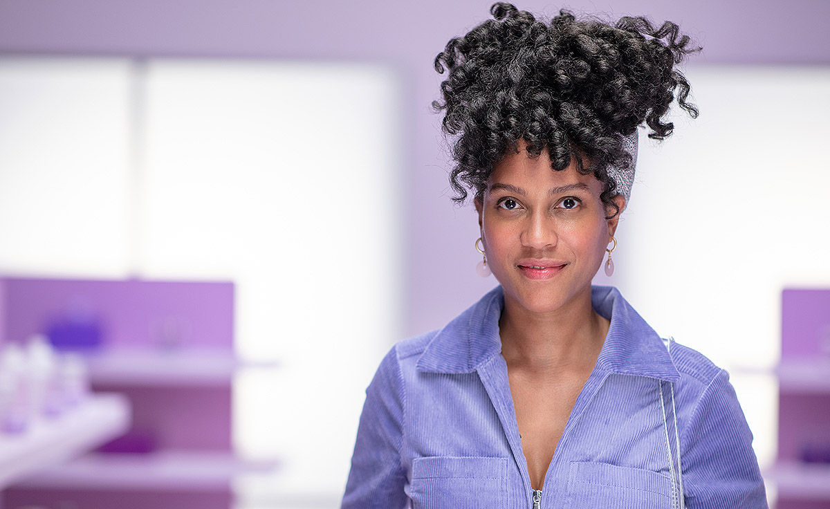 female with curly dark hair and headband wearing purple outfit