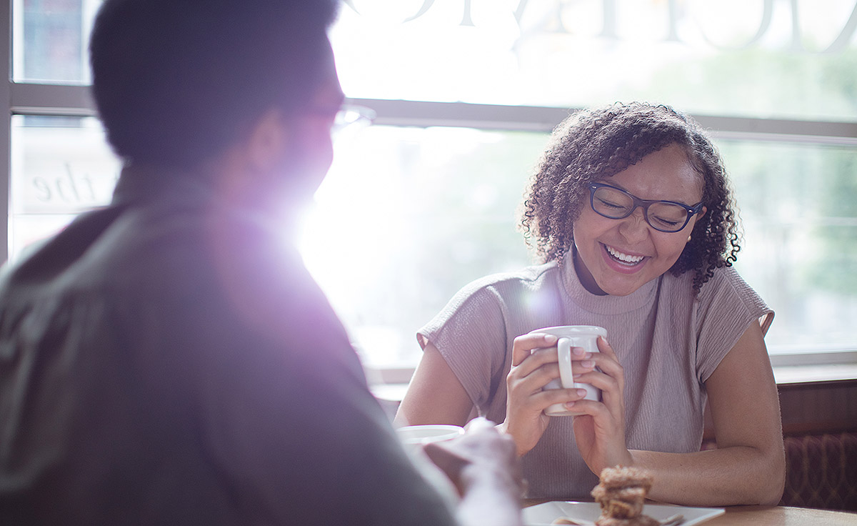 two individuals drinking coffee and eating at table