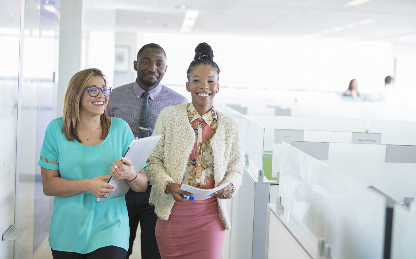 three coworkers walking through corporate office space