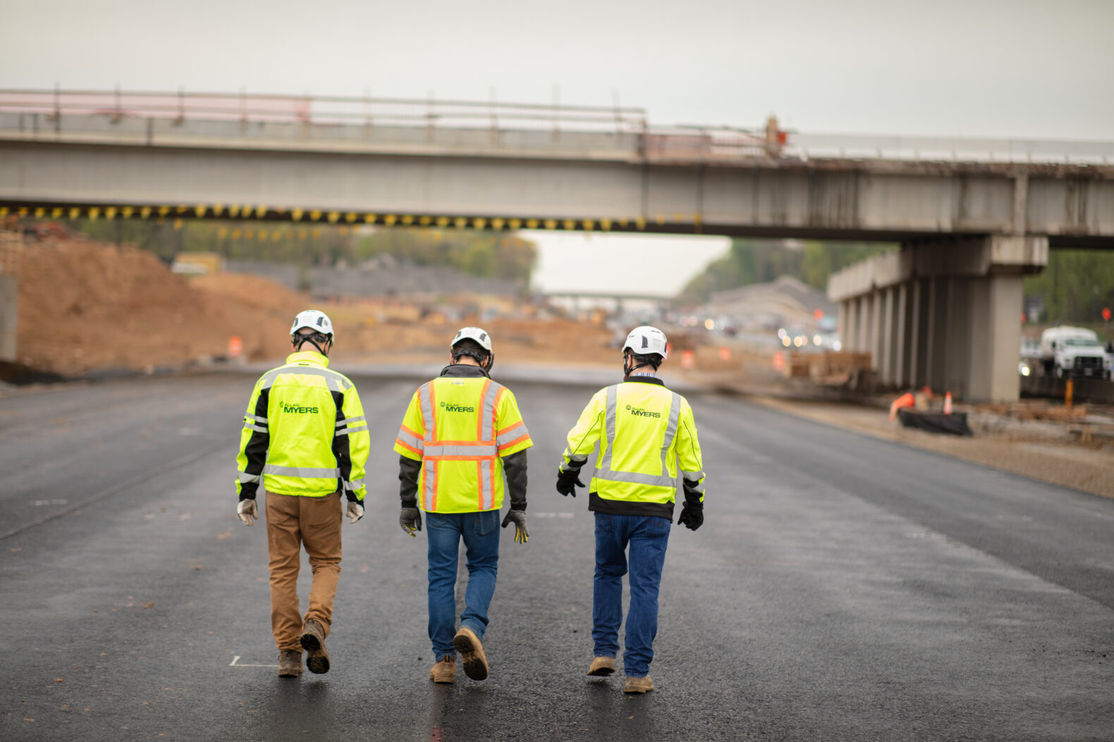 three construction workers walking down road at construction site
