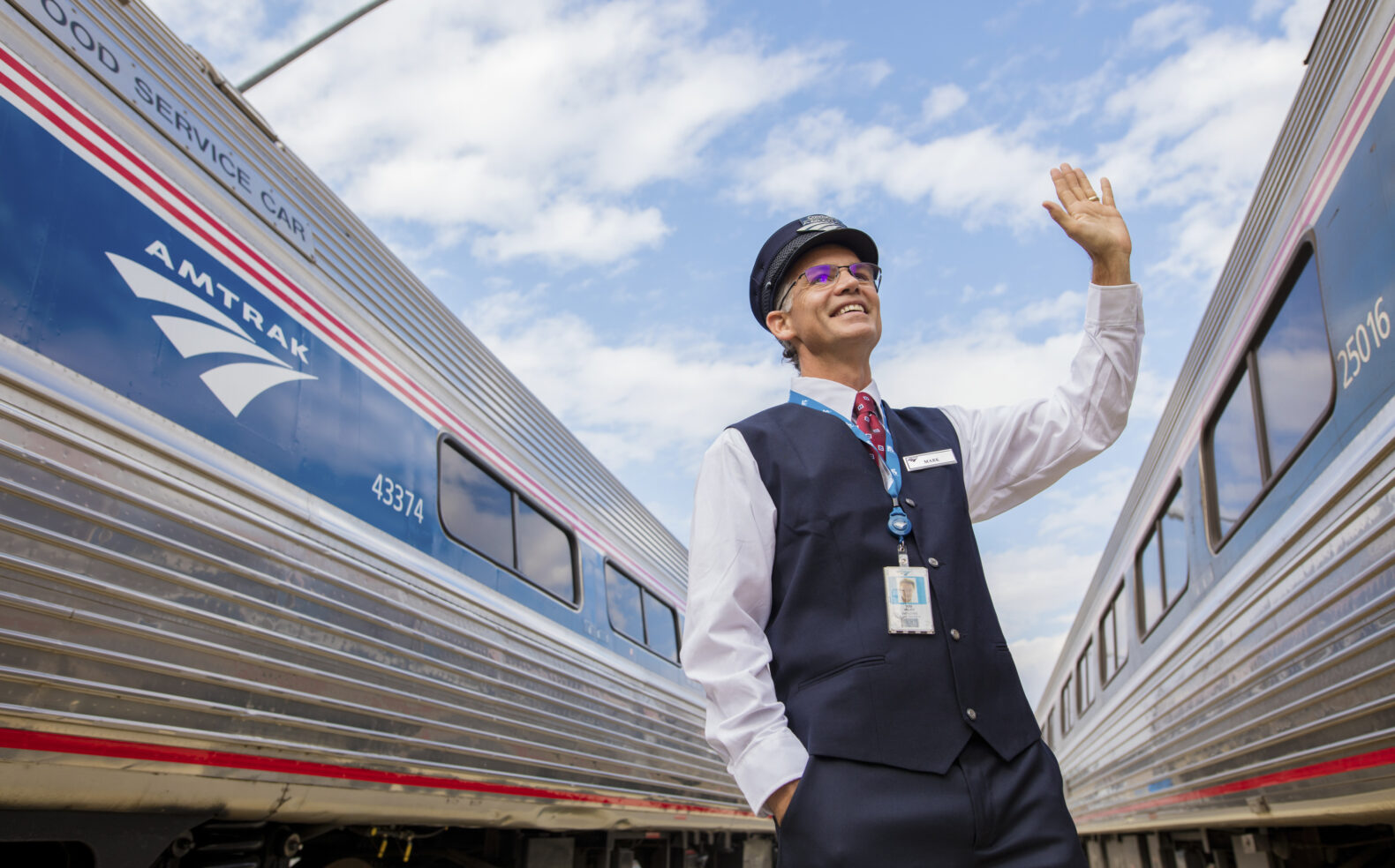 amtrak employee waving to trains as they depart