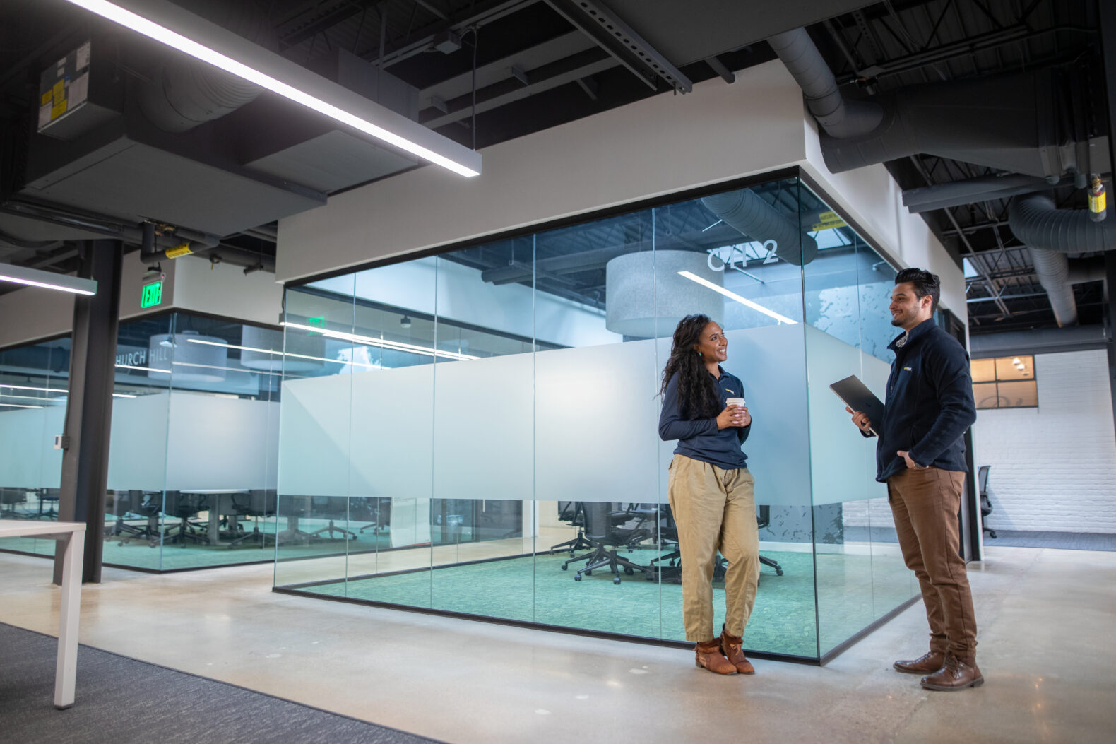 two employees stand outside modern office space collaborating on marketing campaign