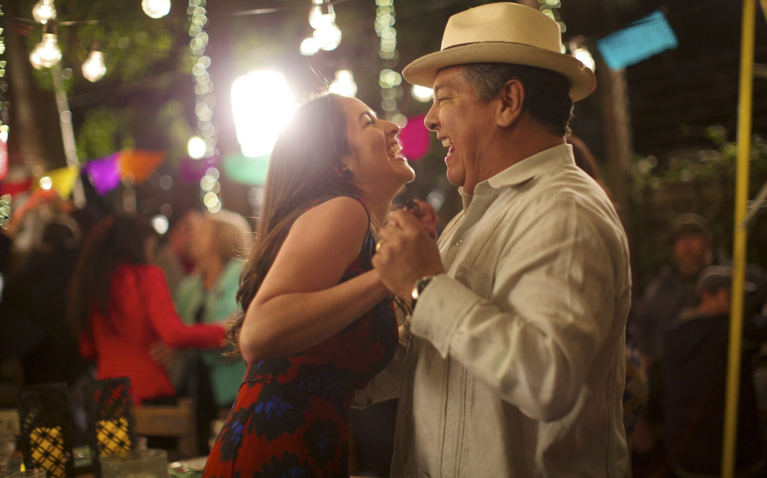 man in fedora and woman dance and laugh at outdoor party