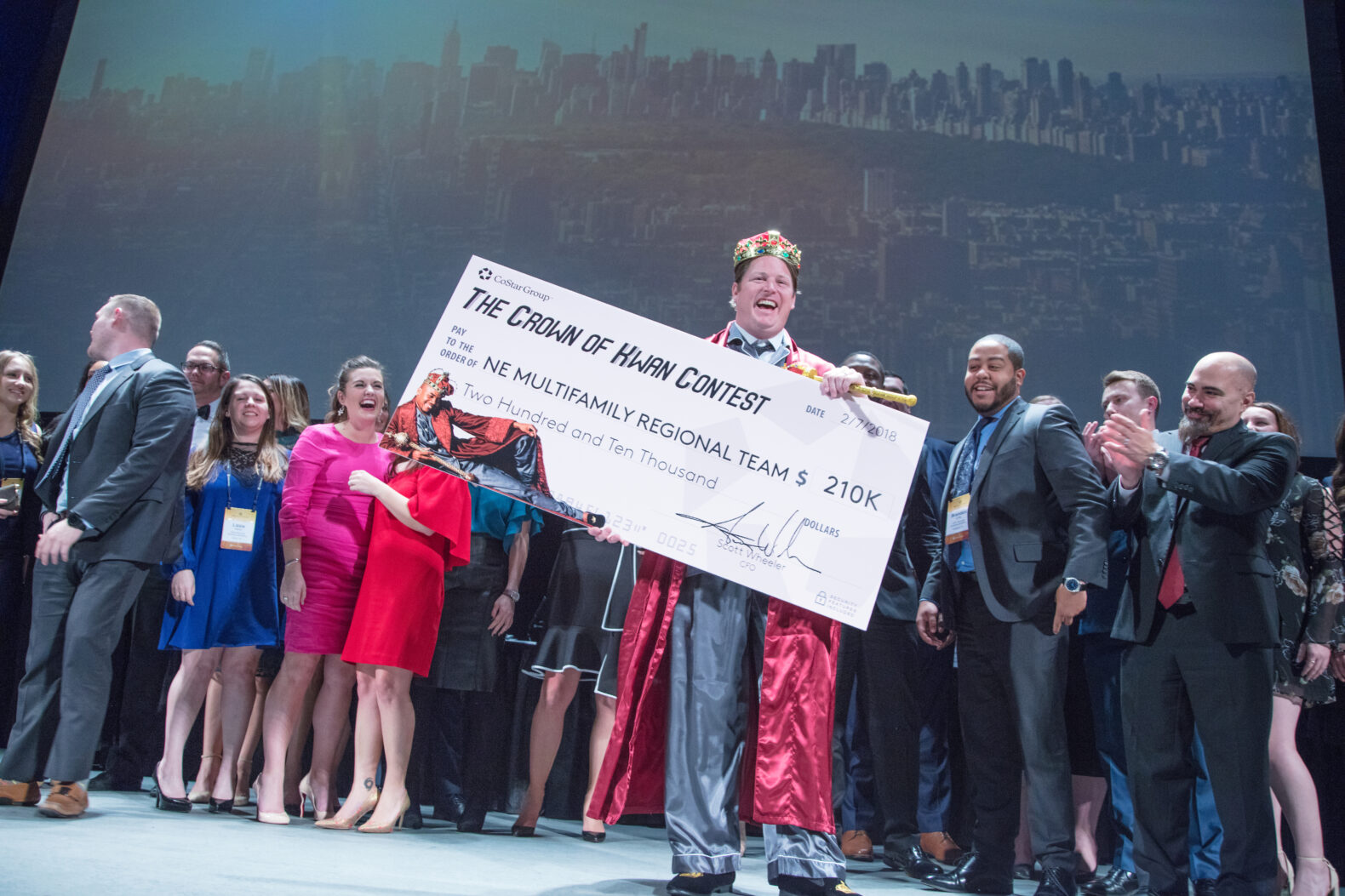 man in crown on stage with large check at corporate event