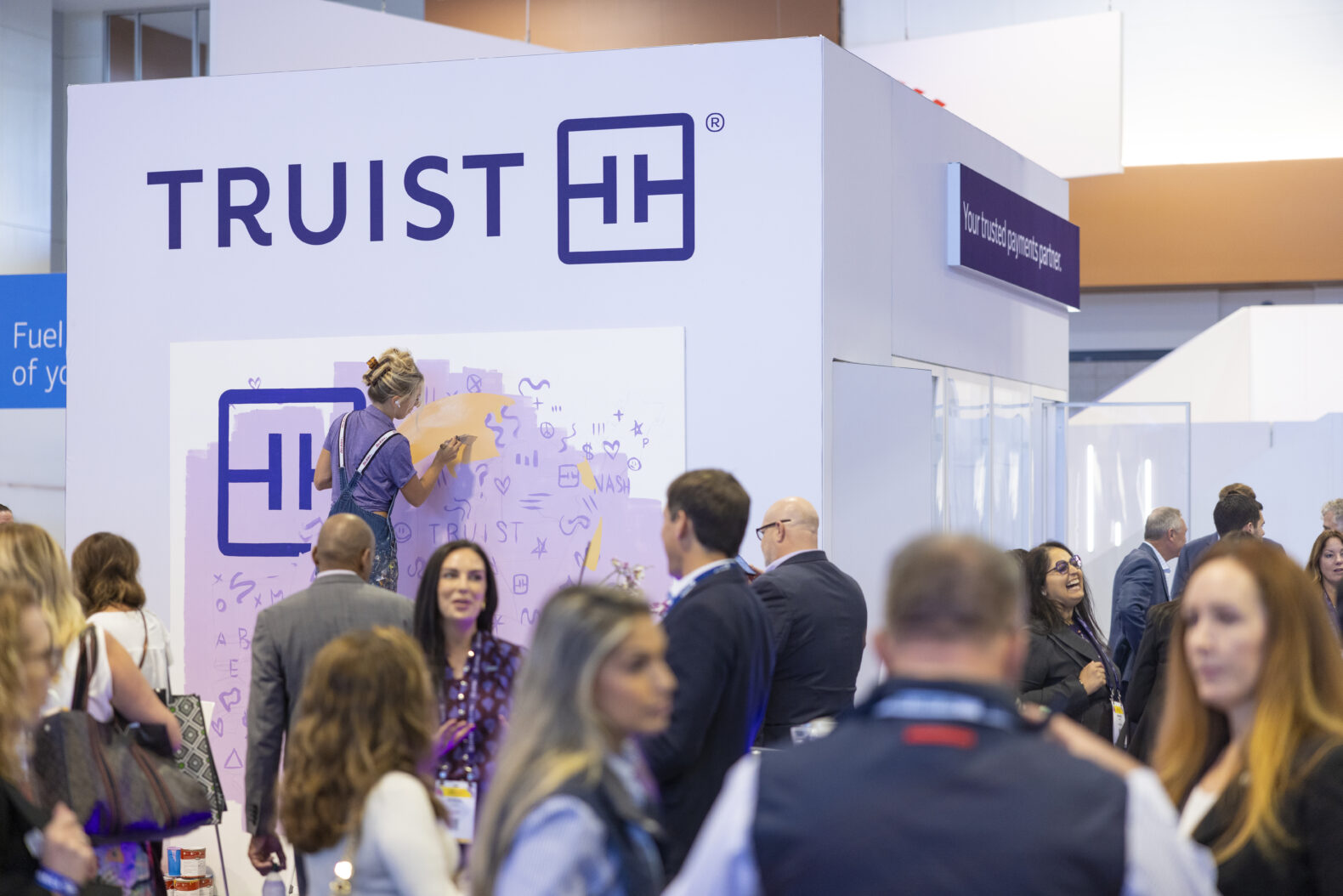 employees gathered at corporate event while artist paints exhibit